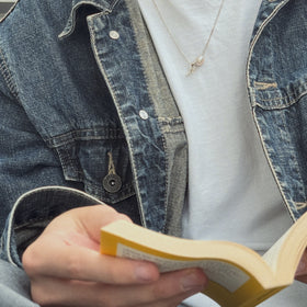 Sisyphus Necklace worn on male model reading a book